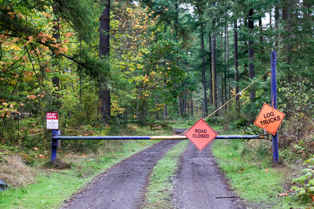 Road closed do not enter log trucks signs on a steel fenceの写真素材