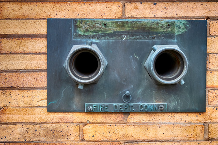 Fire hose nozzles on a building wall in daylightの写真素材
