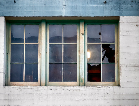 Old building window with panes and broken glass in daylightの写真素材