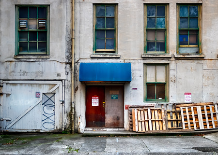 Old building wall with broken windows and doors in daylightの写真素材