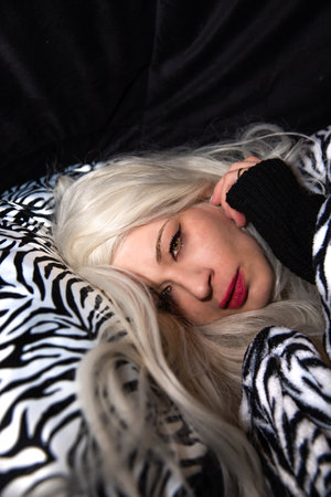 Attractive blonde woman with a tiger striped sheet and pillow with a black backgroundの写真素材