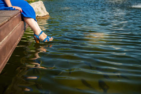 Girl blue shoes sitting lake harmony rest fish water celebrateの写真素材