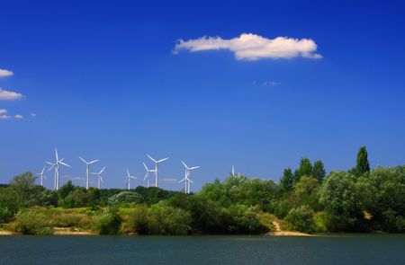 The windmills among trees after second side of lakeの写真素材