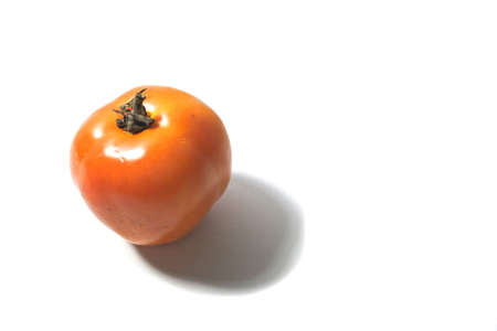 Close up left view single fresh orange tomato isolated on withe background with brown clipping. Single tomato isolated on white backgroundの写真素材