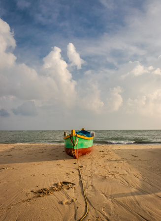 Fishing boat on the yellow sandy beach with clouds and blue sky at dhanushkodi rameswaram india.の写真素材