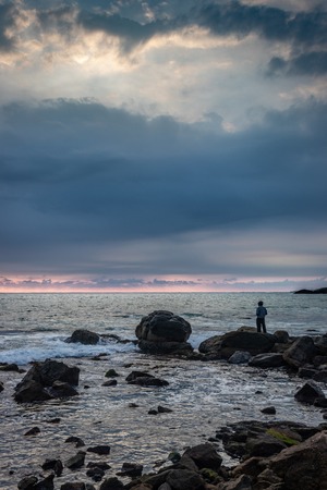 Man watching sea horizon from standing on rock at sunset point kanyakumari tamilnadu india.の写真素材