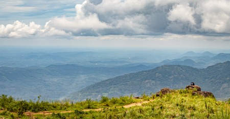 two person sitting on the rock for wide landscape view with hill, blue sky and white clouds.の写真素材