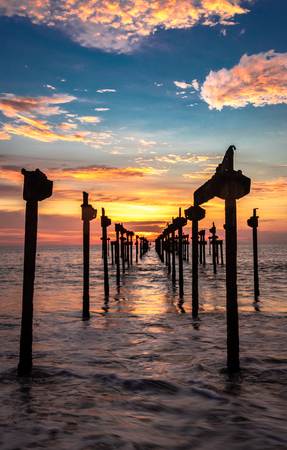 sunset Orange Sky view on the sea water horizon through iron pols taken from low angle at eveningの写真素材