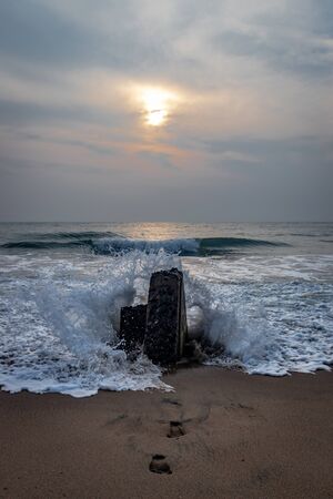 Sunrise over rock and footprints of nature lover in sandy beach of pondicheery india.の写真素材