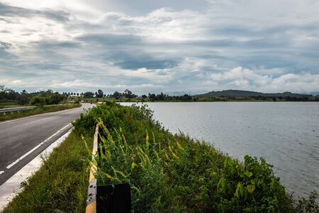 beautiful lake by the side of road with mountain and amazing sky backgroundの写真素材