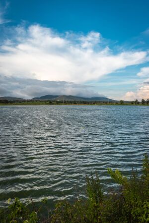 beautiful lake by the side of road with mountain and amazing sky backgroundの写真素材