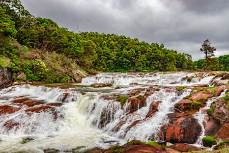 waterfall with red rock and green lush forest flat angle shot image is taken at pykara lake ooty tamilnadu south india. it is showing the beautiful landscape of south india.の写真素材