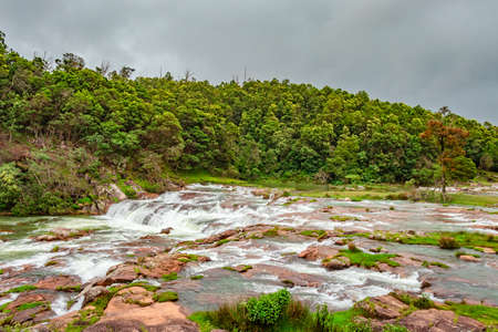 waterfall with red rock and green lush forest flat angle shot image is taken at pykara lake ooty tamilnadu south india. it is showing the beautiful landscape of south india.の写真素材