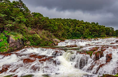 waterfall with red rock and green lush forest flat angle shot image is taken at pykara lake ooty tamilnadu south india. it is showing the beautiful landscape of south india.の写真素材