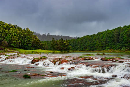 waterfall with red rock and green lush forest flat angle shot image is taken at pykara lake ooty tamilnadu south india. it is showing the beautiful landscape of south india.の写真素材