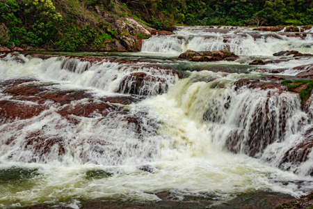 waterfall with red rock and green lush forest flat angle shot image is taken at pykara lake ooty tamilnadu south india. it is showing the beautiful landscape of south india.の写真素材