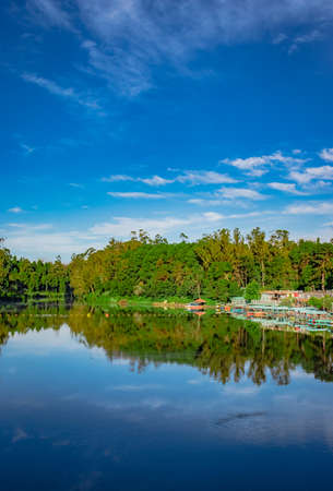 lake pristine with green forest water reflection and bright blue sky at morning image is taken at ooty lake tamilnadu south india. it is showing the beautiful landscape of south india.の写真素材