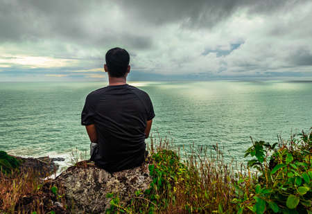 man sitting at mountain cliff enjoying the breathtaking view of sea horizon at morning image is taken at gokarna karnataka india.の写真素材