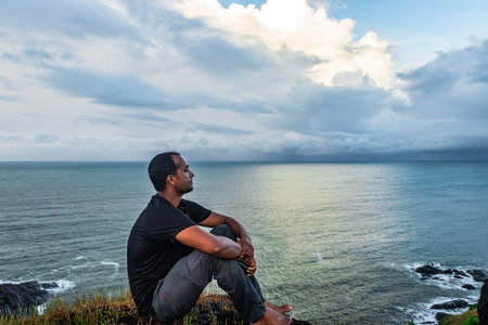 man at hilltop enjoying amazing landscape with sea horizon image is taken at gokarna karnataka india. the view from here is pristine and mesmerizing.の写真素材