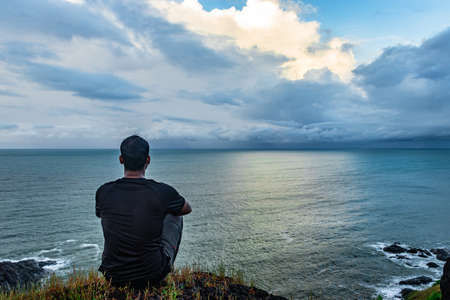 man meditating at hilltop with amazing landscape and sea horizon at morning image is taken at gokarna karnataka india. the view from here is pristine and mesmerizing.の写真素材