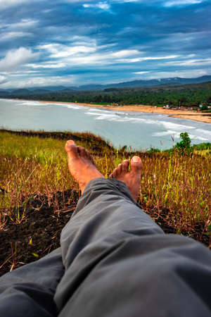 hiker resting at hilltop with breathtaking mountain view in background image is taken at gokarna karnataka india. it is showing the human love towards the nature.の写真素材