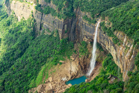 waterfall streams falling from mountain top covered with green forests at day image is taken at Nohkalikai Falls cherrapunji meghalaya india. it is the tallest plunge waterfall in Indiaの写真素材