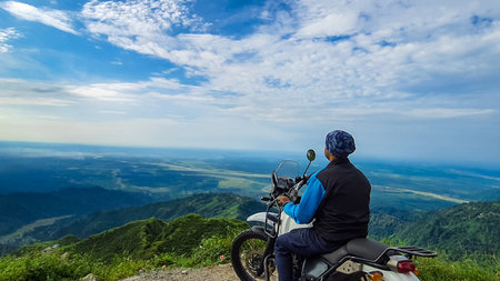 young man biker sitting on bike at mountain top with mesmerizing view at morning image is taken at kurseong darjeeling west bengal india.の写真素材