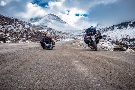 man solo traveler at isolated tarmac road with snow cap mountains in background at morning image is taken at sela pass tawang arunachal pradesh india.の写真素材