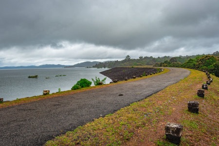 river serene back water with remote tarmac road and dramatic cloudy sky image is taken at Supa Dam dandeli karnataka india. The backwaters is totally stunning.の写真素材