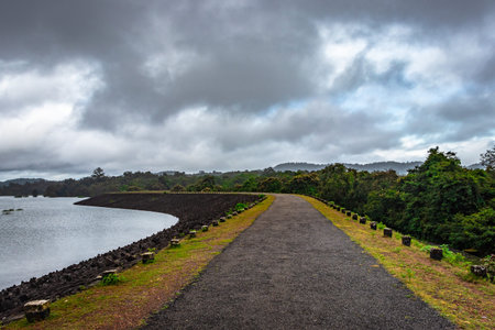 river serene back water with remote tarmac road and dramatic cloudy sky image is taken at Supa Dam dandeli karnataka india. The backwaters is totally stunning.の写真素材
