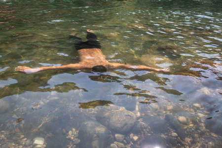 boy meditating inside serene transparent lake water image is taken at dwaki lake meghalaya india.の写真素材