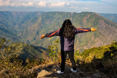 girl showing victory sign at mountain range with amazing sky landscape image is taken at meghalaya india. it is showing the serene beauty of north east india.の写真素材