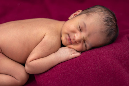 newly born baby laying on red velvet cloth with cute facial expression from different angleの写真素材