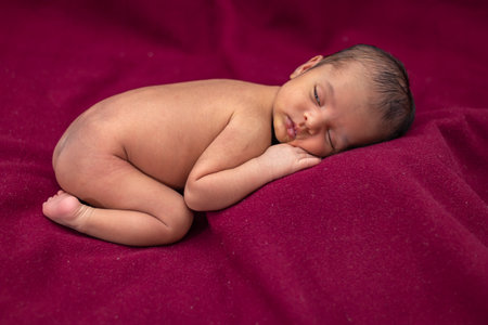 newly born baby laying on red velvet cloth with cute facial expression from different angleの写真素材