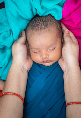 mom touching cute newborn baby sleeping in baby wrap top angle shot