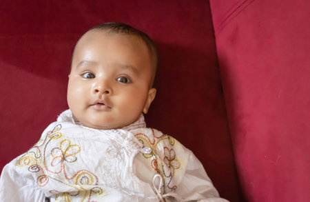 infant boy in traditional indian outfit lying on sofa cute facial expression at indoor