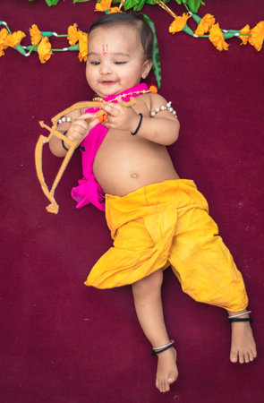 cute Indian boy dresses as lord rama with bow and flowers from top angle