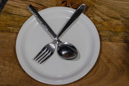 isolated white plate with spoon and fork showing no more food required