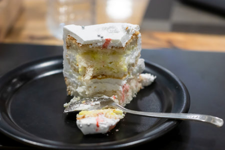 sliced birthday vanilla cake served at black plate with spoon