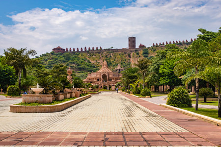 artistic carved red stone jain temple with bright blue sky at morning from unique angle image is...