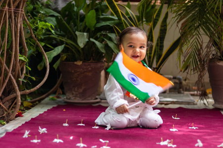 cute toddler holding indian tricolor flag in traditional cloth with innocent facial expressionの写真素材