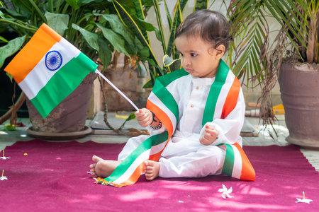 cute toddler holding indian tricolor flag in traditional cloth with innocent facial expression