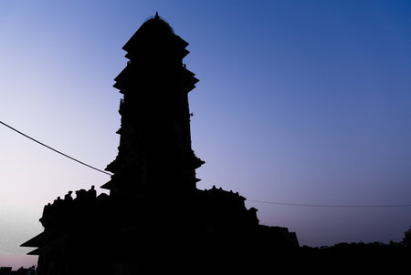 backlit view of historical clock tower ancient architecture with bright blue sky at sunsetの写真素材