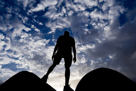 backlit shot of isolated man standing at wall watching sunset with dramatic sky at dusk