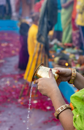 holy water offerings by indian devotee doing traditional rituals at chhath festival at morning