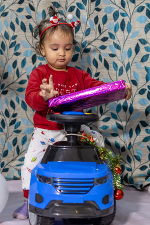 cute infant enjoying Christmas eve celebration with kid car gift at home at night