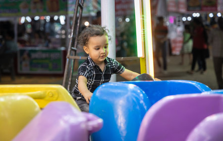 isolated indian kid enjoying baby joy ride at local fair from different angleの写真素材
