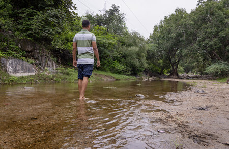 Isolated Man Walking in Natural River Stream During Morningの写真素材