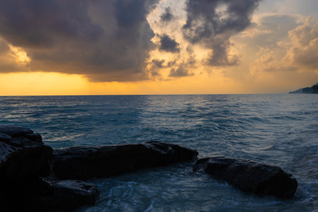 sunrise dramatic sky over sea horizon from rocky shore at dawn long exposure shotの写真素材
