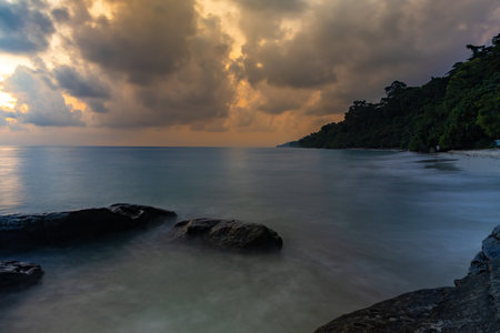 sunrise dramatic sky over sea horizon from rocky seashore at dawn long exposure shotの写真素材